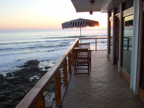 a porch with two chairs and an umbrella and the ocean at taghazout playa in Taghazout