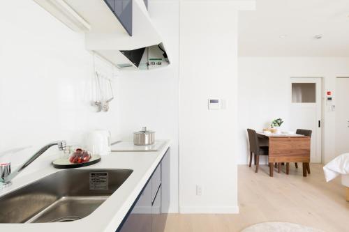 a white kitchen with a sink and a table at サンライズハワイ in Osaka