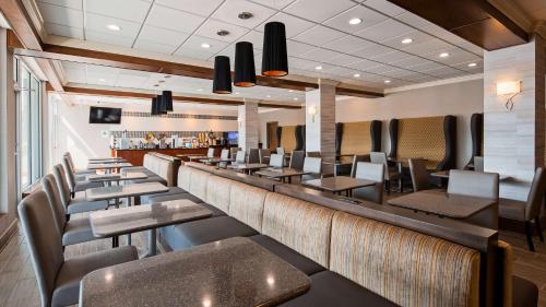 a restaurant with a long bar with chairs and tables at Cottonwood Airport & Expo Hotel Louisville in Louisville