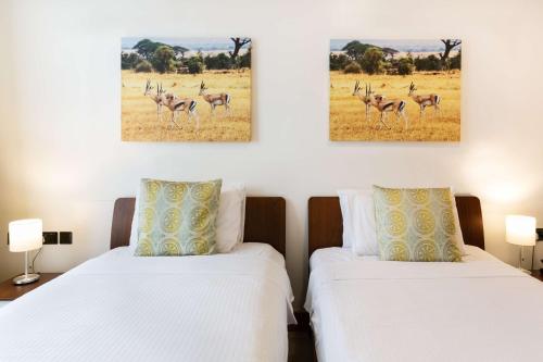 two beds in a room with two paintings on the wall at Executive Residency by Best Western Nairobi in Nairobi