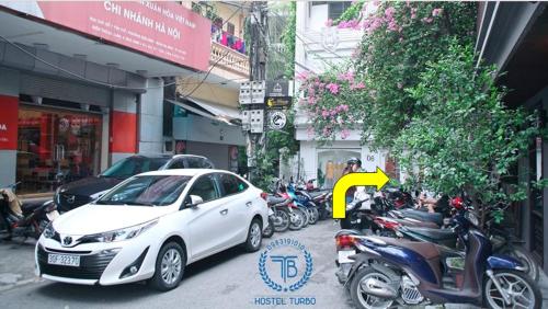 a white car parked next to a row of motorcycles at HOSTEL TURBO in Hanoi