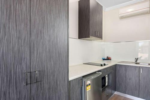 a kitchen with wooden cabinets and a sink and a counter at Comfort Inn Moree in Moree
