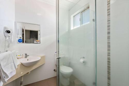 y baño blanco con lavabo y ducha. en Econo Lodge Moree Spa Motor Inn, en Moree