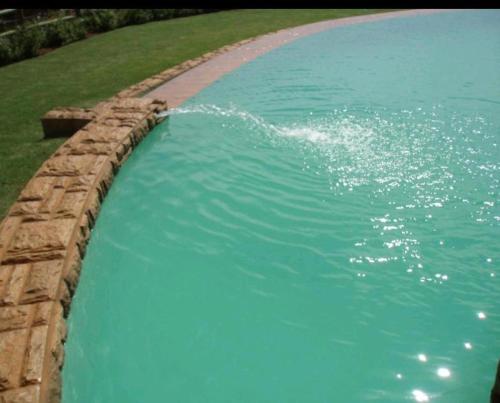 une grande piscine d'eau avec un mur en pierre dans l'établissement Ocean View Villas A08, à Port Edward