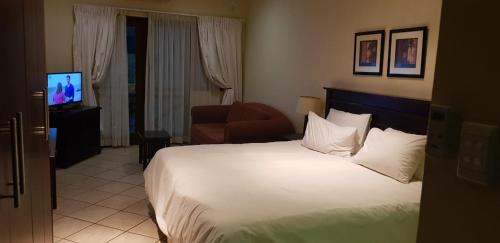 a hotel room with a bed and a chair and a television at Ocean View Villas A08 in Port Edward