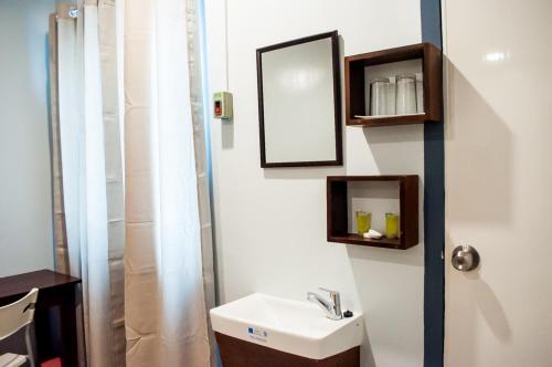 a bathroom with a sink and a mirror and a shower at Seasons Hotel Sablayan in Buenavista