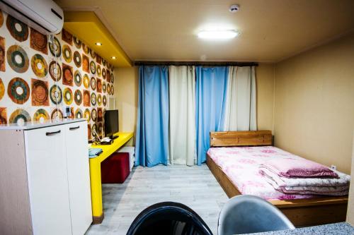 1 dormitorio con cama, escritorio y cocina en Wind Come Pension Gyeongju, en Gyeongju