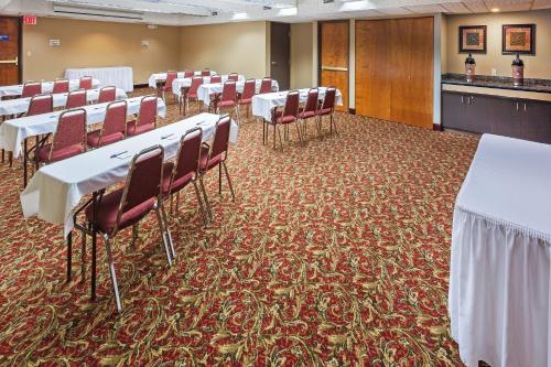 a conference room with white tables and red chairs at AmericInn by Wyndham Omaha in Omaha