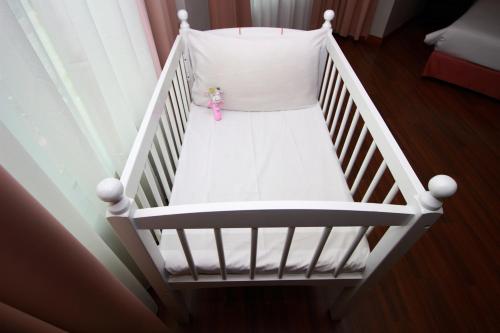 a white crib with a doll sitting on it at Grand Kampar Hotel in Kampar