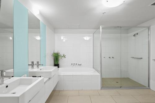 a white bathroom with two sinks and a shower at Melbourne Holiday Apartments Flinders Wharf in Melbourne