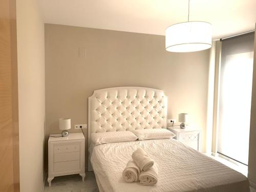 a bedroom with a white bed with two slippers on it at Apartment Lucena Center Bajo in Lucena