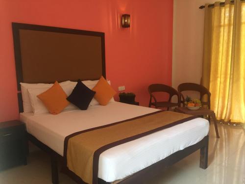 a bedroom with a large bed with orange walls at Organic Garden Resort Sigiriya in Sigiriya