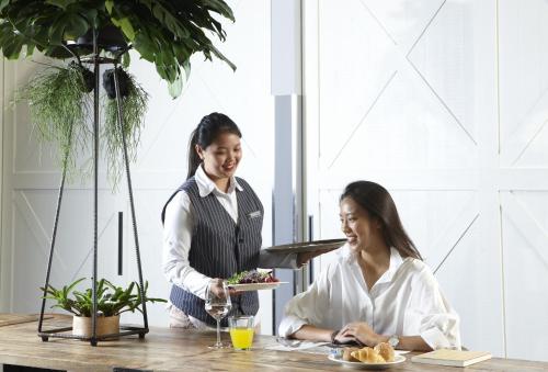 two women sitting at a table with a plate of food at Just Sleep - Sanchong in Taipei