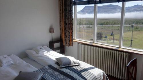 a bedroom with a bed and a large window at Hotel Stadarborg in Breiðdalsvík