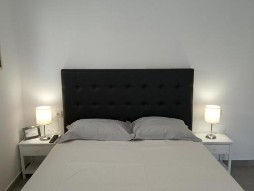 a bed with a black headboard and two tables with lamps at Casa do Sol - 70 m from the beach in Nazaré