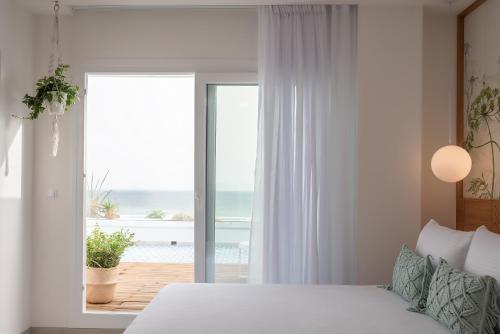 a bedroom with a bed and a view of the ocean at Alzocaire Hostal Boutique in Conil de la Frontera
