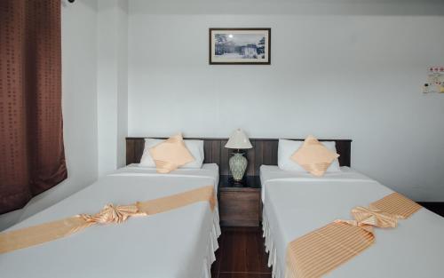 two beds in a room with white sheets and bows at Iyara Hua Hin Lodge in Hua Hin
