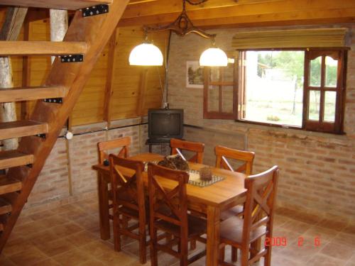 a dining room with a wooden table and a television at Cabañas Ecos del Rio in Los Reartes