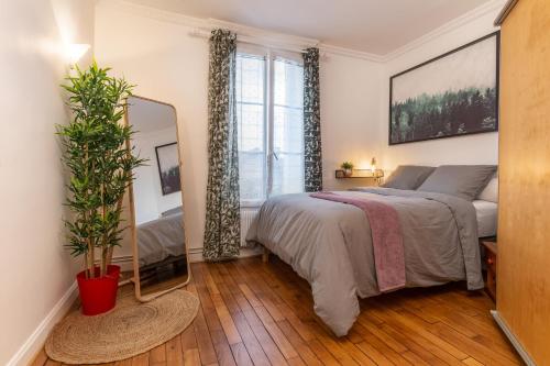 een slaapkamer met een bed en een spiegel en een plant bij Proche Paris, Confort, Wifi, Netflix in Deuil-la-Barre
