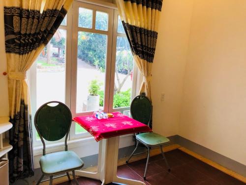 - une table et deux chaises dans une chambre avec fenêtre dans l'établissement Khách sạn Hương Mê, à Buôn Ma Thuột