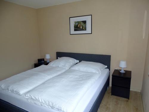 una camera da letto con un letto con lenzuola bianche e due lampade di Ferienwohnung am Berggrabenweg a Ilmenau