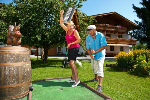 an older man and woman playing golf in a yard at Hotel Quehenberger in Maishofen