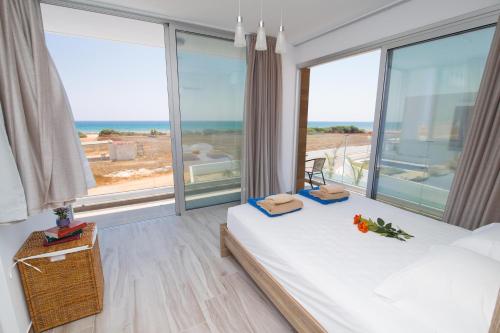 a bedroom with two beds and a large window at Villa Lynn Boutique Beachfront in Ayia Napa
