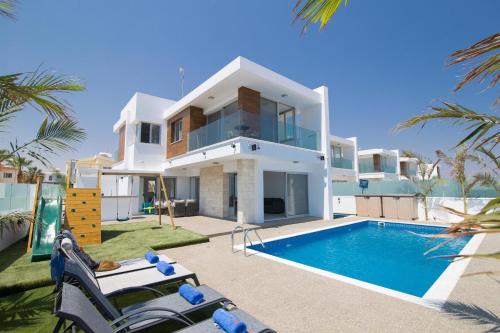 a villa with a swimming pool in front of a house at Villa Lynn Boutique Beachfront in Ayia Napa
