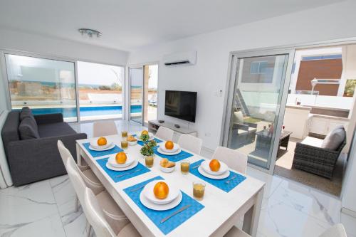 a dining room and living room with a table and chairs at Villa Lynn Boutique Beachfront in Ayia Napa