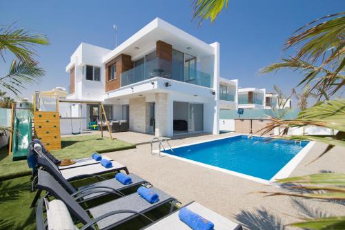 a villa with a swimming pool in front of a house at Villa Lynn Boutique Beachfront in Ayia Napa