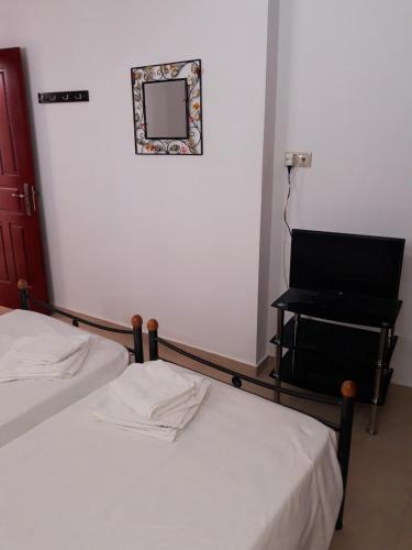 a room with two beds and a desk with a piano at Stegnailion in Archangelos