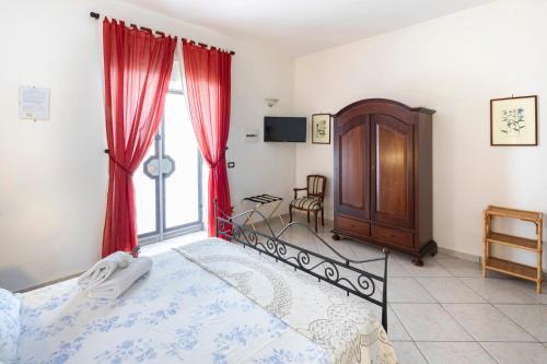 a bedroom with a bed with red curtains and a window at Relais Masseria Casiello in San Castrese
