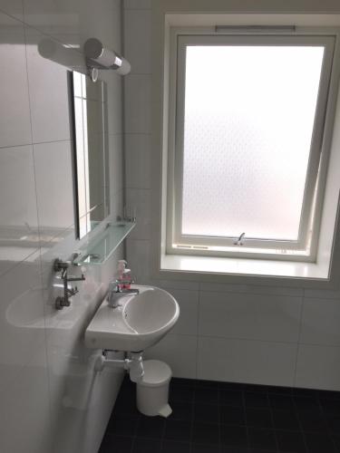 baño blanco con lavabo y ventana en Lovely 3 rooms apartment for holiday in Nyksund, en Nyksund