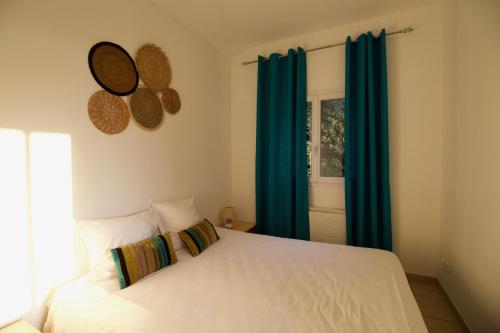 a bedroom with a bed with blue curtains and a window at Hôtel Sampiero in Propriano