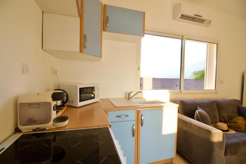 a small kitchen with a couch and a microwave at Hôtel Sampiero in Propriano