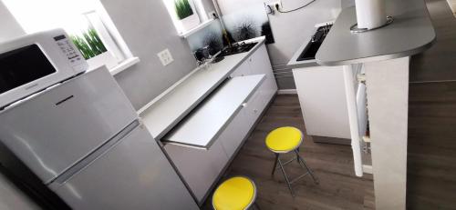 uma cozinha com um lavatório e 2 cadeiras amarelas em Garsoniera Ultracentral em Constança