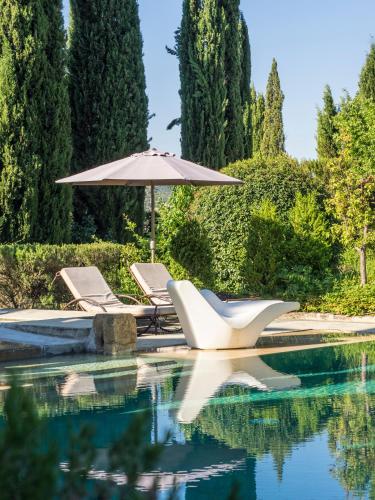- une piscine avec 2 chaises longues et un parasol dans l'établissement B&B Contemporain Le Jardin, à Vaison-la-Romaine