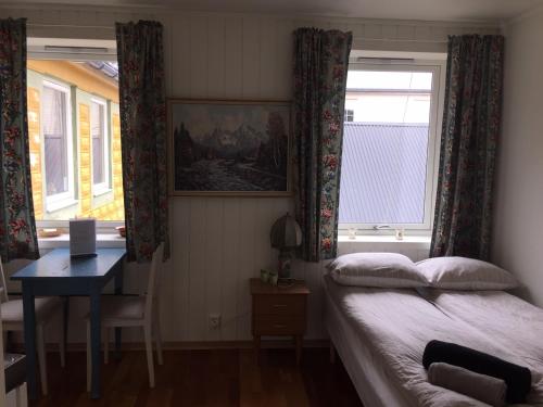 1 dormitorio con cama, escritorio y ventana en Cute small apartment on the pier in Nyksund, en Nyksund