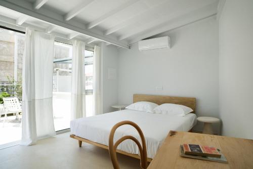 a white bedroom with a bed and a table at City Centre Rooms in Limassol
