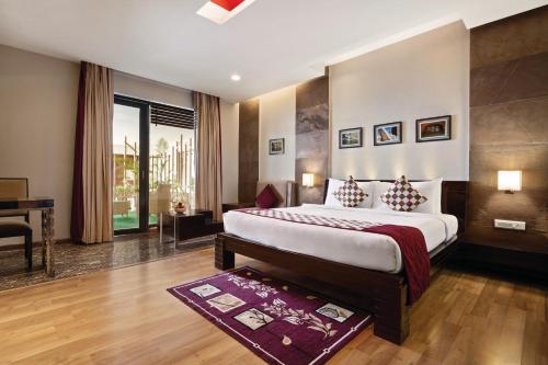 a bedroom with a bed and a desk in a room at Ramada Ajmer in Kishangarh