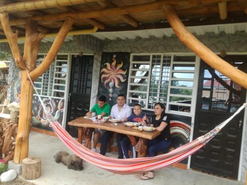 a group of people sitting at a table in a hammock at Cabañas Guacari San Agustín huila in San Agustín