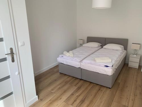ein kleines Bett in einem Zimmer mit Holzboden in der Unterkunft Apartament w centrum in Mrągowo