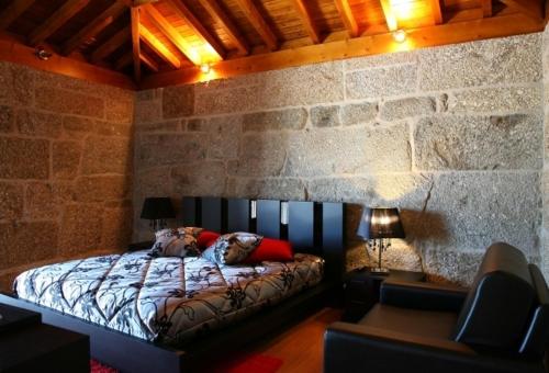 - une chambre avec un lit et un mur en pierre dans l'établissement Quinta Do Passal, à Paços de Ferreira