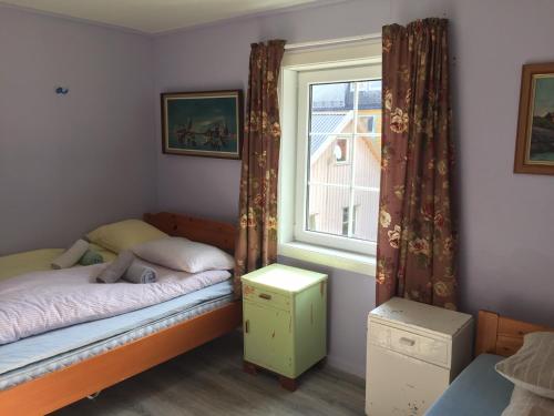 ein kleines Schlafzimmer mit einem Bett und einem Fenster in der Unterkunft Holiday in the former fishing factory Arntzen-brygga in Nyksund