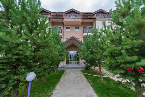 a large pink building with trees in front of it at Thermal Hotel Seven Seasons in Banya