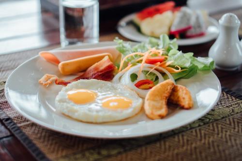 a plate of breakfast food with eggs bacon and vegetables at Iyara Hua Hin Lodge in Hua Hin