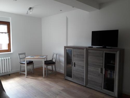 ein Wohnzimmer mit einem TV und einem Tisch mit Stühlen in der Unterkunft Ferienwohnung in Gadsdorf