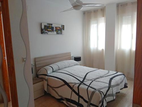 een slaapkamer met een bed en een plafondventilator bij Fantastico Apartamento con solárium in Los Alcázares