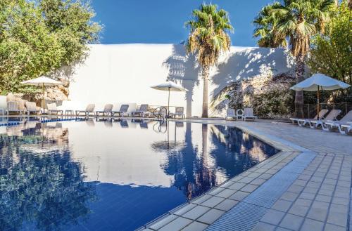 a pool with chairs and umbrellas and palm trees at Mövenpick Hotel Amman in Amman