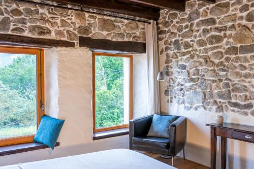 a bedroom with two chairs and a stone wall at B&B MaisonNel in Saint-Bonnet-en-Champsaur